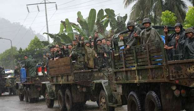 Philippine marines aboard their trucks flash the victory sign as they start their pull-out from the main battle area in Marawi on the southern island of Mindanao