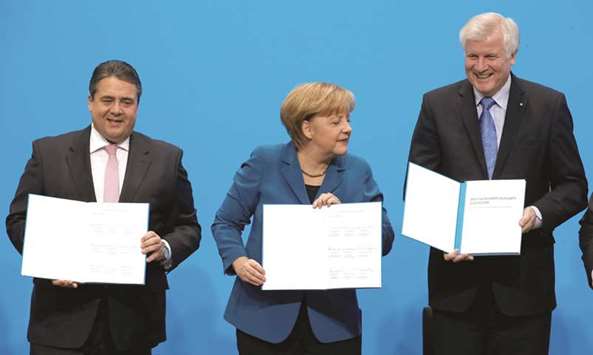 File photo: German Chancellor Angela Merkel (centre), leader of the Christian Democratic Union (CDU); Horst Seehofer (right), leader of the Christian Social Union (CSU); and Sigmar Gabriel, leader of the Social Democratic Party (SPD), hold copies of a signed coalition treaty during a ceremony in Berlin in December 2013.