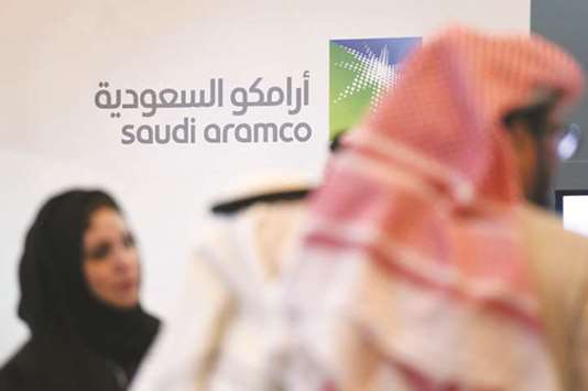 Saudi and foreign investors stand in front of the logo of state oil firm Aramco during a competitiveness forum in the capital Riyadh (file). A factor influencing Saudi oil policy is the planned sale of close to 5% of national oil conglomerate Aramco in an Initial Public Offering (IPO) next year.
