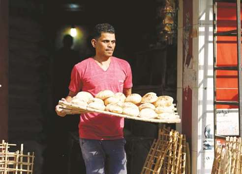 An Egyptian man carries bread at a vegetable market in Cairo. Subsidised bread is a staple for millions of poor Egyptians and the countryu2019s leaders are always keen to keep supplies flowing for fear of unrest.