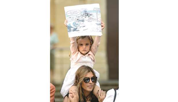 A child holds up a sign depicting the scene of the car bomb blast that killed Caruana Galizia.