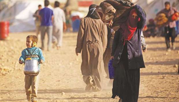 Displaced Syrians from Deir Ezzor walk at a camp for internally displaced people in Ain Issa.