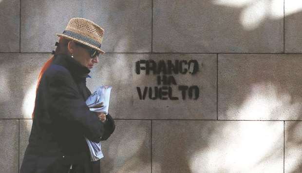 A woman walks near graffiti reading u2018Franco is backu2019 on the wall of a building in Barcelona.