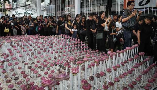 People walk past an elaborate lotus flower display made in honour of the late Thai king Bhumibol Adu