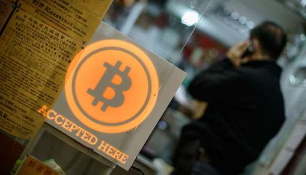 A man talking on a mobile phone in a shop displaying a bitcoin sign during the opening ceremony of the first bitcoin retail shop in Hong Kong.