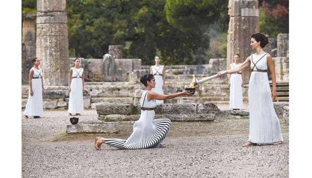 Actress Katerina Lechou (right), acting as the high priestess, lights the Olympic flame at the Temple of Hera in Olympia, the sanctuary where the Olympic Games were born in 776 BC, during the lighting ceremony of the Olympic flame for the 2018 Winter Olympics, yesterday. The 2018 Winter Games will take place in Pyeongchang, South Korea from February 9 to February 25. (AFP)