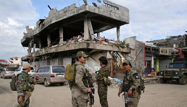 Soldiers stand on guard in front of a damaged building  in Marawi City