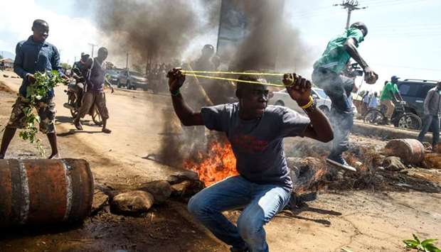 Supporters of National Super Alliance (NASA) presidential candidate Raila Odinga throw rocks next to burning tyres blocking the road, during a demonstration on the boycott of the upcoming elections
