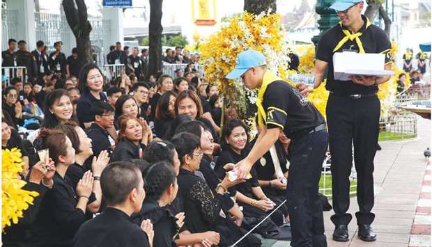 Prince Dipangkorn Rasmijoti (second right), 12, handing out food and water to well-wishers in Bangkok yesterday.