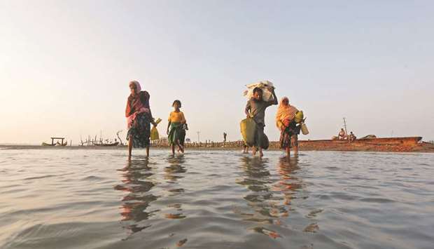 Rohingya refugees walk through water after crossing the Bangladesh-Myanmar border, at a port in Teknaf, Bangladesh.