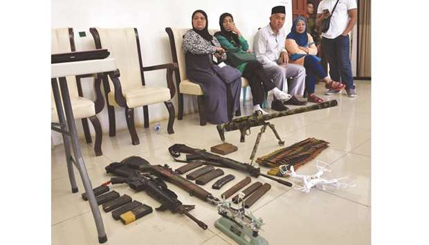 Residents waiting for their safe conduct papers, watch as soldiers display home-made barrett sniper, and other weapons recovered from militants in Marawi.