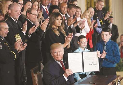 With First Lady Melania Trump behind him, President Trump displays a signed presidential  memorandum during an event highlighting efforts to battle the opioid crisis in the US.