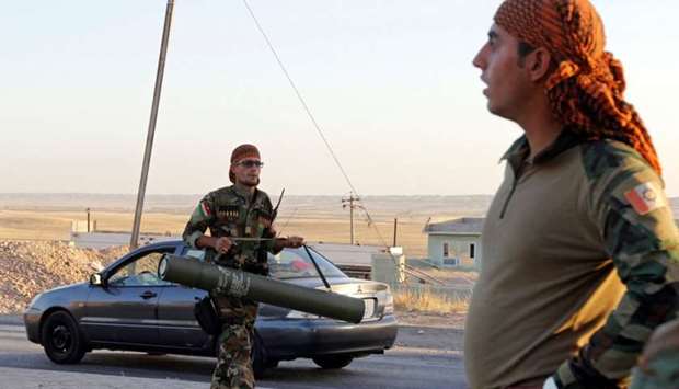 A Kurdish Peshmarga fighter carries a rocket in north of Kirkuk, Iraq