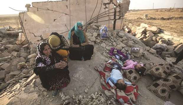 An Iraqi family sits on the rubble of their home in the village of Barzan, in the Zummar area of Nineveh province, northwest of Mosul, yesterday.