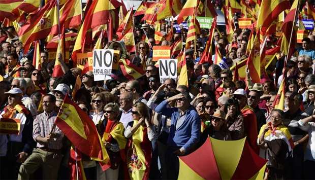 People hold signs reading ,No to the coup, while waving Spanish flags during a demonstration calling for unity at Plaza de Colon in Madrid