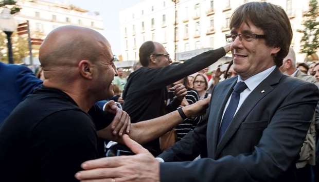 Catalan regional president Carles Puigdemont (R) is greeted by residents in Girona