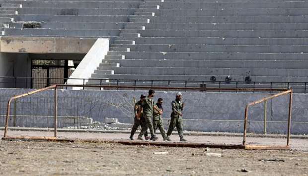 Fighters of Syrian Democratic Forces walk at the stadium in Raqqa, Syria
