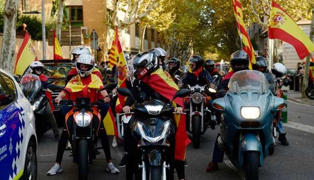 Some people on bikes ride wrapped in Spanish and Catalan flags during a demonstration calling for unity in Barcelona