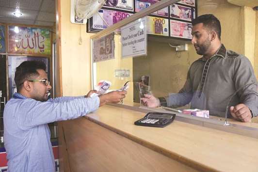 This photograph taken on October 19, 2017 shows a visiting dual Pakistani Kashmiri and British citizenship holder (left) exchanging British pounds at a remittance shop in the Pakistani Kashmir city of Mirpur, which is known as u201cLittle England.u201d With few jobs and little industry, the residents of Pakistanu2019s u201cLittle Englandu201d overwhelmingly rely on family members based in Britain for their economic livelihood.