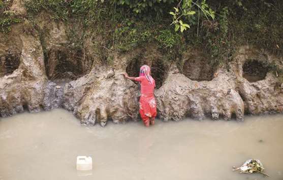A Rohingya refugee woman collects water from a shallow well, dug from the sand along a drain at Uchiprang refugee camp near Coxu2019s Bazar, Bangladesh yesterday.