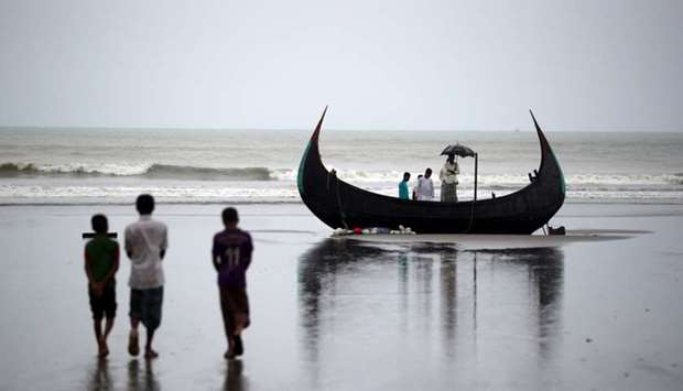 People look at a boat that capsized with a group of Rohingya refugees in it at Bailakhali, near Cox's Bazar, Bangladesh
