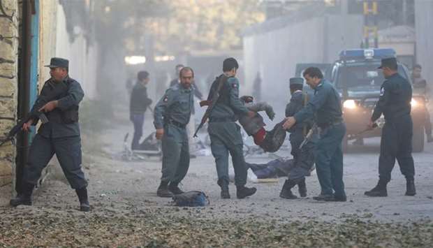 Afghan policemen carry an injuried after a blast in Kabul, Afghanistan