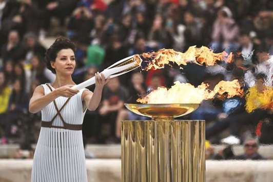 Actress Katerina Lechou, playing a high priestess, lights a torch during the handover ceremony of the Olympic flame for the 2018 Winter Olympics in Pyeongchang at the The Panathenaic Stadium in Athens yesterday. (AFP)