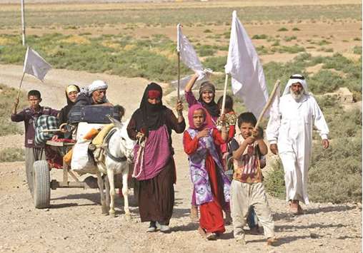 Members of an Iraqi family, displaced from the outskirts of Islamic State (IS) group stronghold Hawija, raise white flags while travelling with a donkey-cart on the road outside the town yesterday, as Iraqi forces advance to recapture the town.
