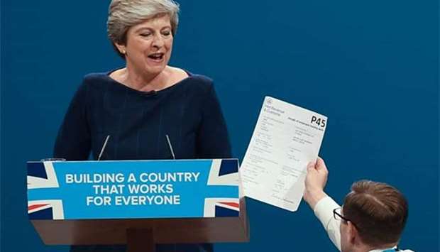 Protester comedian Simon Brodkin gives a piece of paper written as a mock P45 (employee leaving form) to Prime Minister Theresa May in Manchester on Wednesday.