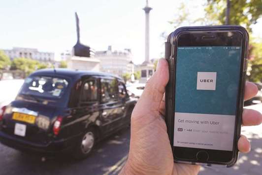 A London taxi passing as the Uber app logo is displayed on a mobile telephone in London. SoftBank will invest $1bn to $1.25bn in Uber at last yearu2019s valuation of about $70bn, sources said yesterday.