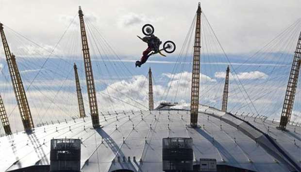 Action sports performer Travis Pastrana somersaults on his motorbike as he jumps between two barges on the River Thames with the O2 Arena sports venue seen behind, in London on Thursday.