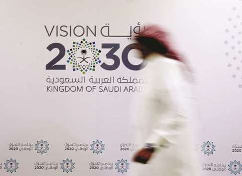 A Saudi man walks past the logo of Vision 2030 in Jeddah (file). Data released this week showed Saudi Arabia in recession during the second quarter while the non-oil  sector expanded only 0.6% from a year earlier.