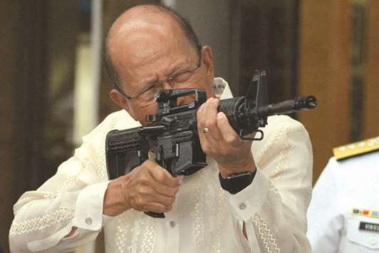 Philippine Defence Secretary Delfin Lorenzana tries a CQ-A5b rifle donated by the Chinese government during the ceremony at the military headquarters in Manila yesterday.