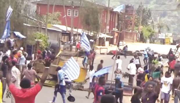 This still image taken from a video shot on October 1 shows protesters waving Ambazonian flags in front of road block in the English-speaking city of Bamenda.