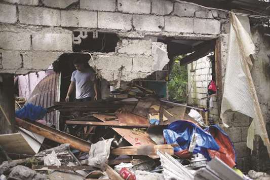 A man walks amongst debris of damaged houses after a water tank exploded in Bulacan, east of Manila, yesterday.