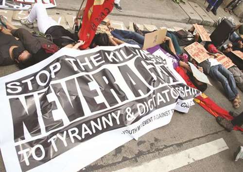 Members of various groups lie down in front of the Caloocan Police District office in protest over the killing of drug suspects.