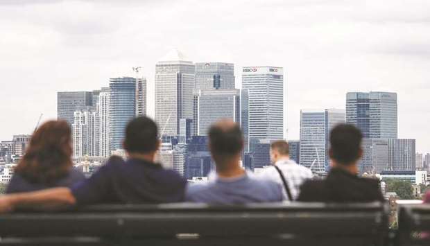 People look at the view of the Canary Wharf financial, shopping and business district, from Greenwich Park in London. Britain has long struggled to squeeze more output from its workers as many companies have been hiring extra staff rather than investing in new equipment.