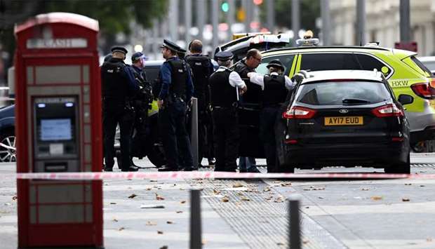 Police officers stand next to and enter a car in the road near the Natural History Museum, after a car mounted the pavement, in London