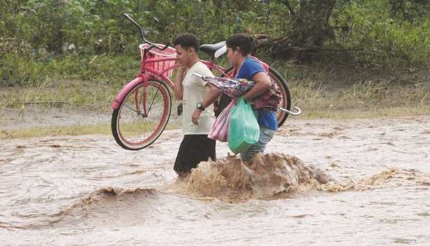 Local residents cross a river flooded by heavy rains by Tropical Storm Nate in Nandaime town, Nicaragua, on Friday.