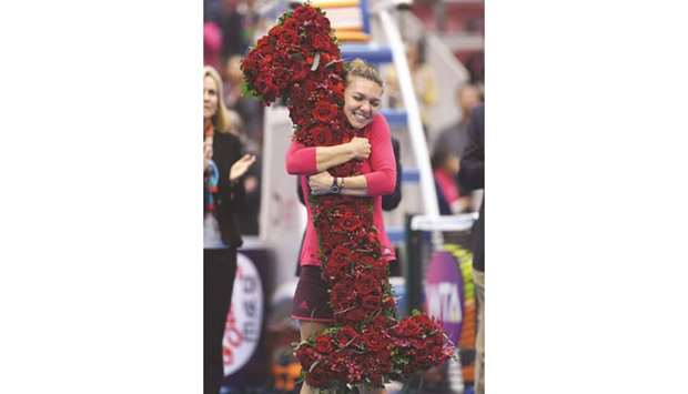 Simona Halep of Romania celebrates after being presented with a bouquet in the shape of the number u20181u2019, after taking the top ranking by winning her semi-final against Jelena Ostapenko of Latvia at the China Open in Beijing yesterday. (AFP)