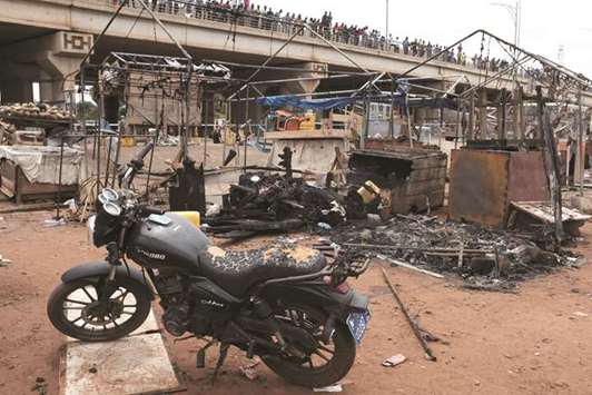 People stand on a bridge as they inspect the damage at the site of an explosion at a fuel distribution site in Accra, Ghana, yesterday.