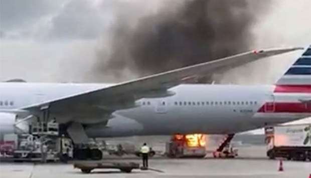Smoke billows from loading equipment after it caught fire next to an American Airlines plane at Hong Kong International Airport.