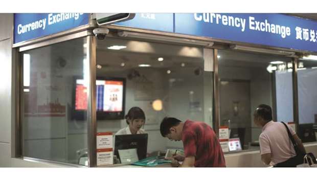 A man changes foreign currency into Chinese yuan at a currency exchange office in Hongqiao airport in Shanghai (file).  JPMorgan Chase & Co is expecting the yuan to drop to 7.01 per dollar by the end of December and 7.19 by September 2019, after previously projecting it at 7.02 in 12 monthsu2019 time.
