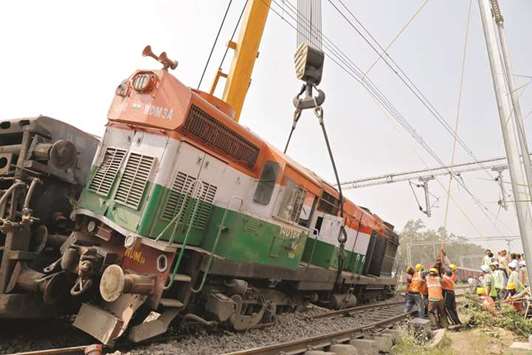 Rescuers move a damaged engine of a passenger train after it derailed in Harchandpur, in the northern state of Uttar Pradesh, yesterday.