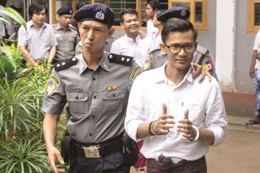 Detained Myanmar journalists Kyaw Zaw Lin, (front), Phyo Wai Win (4th, left) and Nayi Min (left) leave the courthouse escorted by police after appearing before the court yesterday.