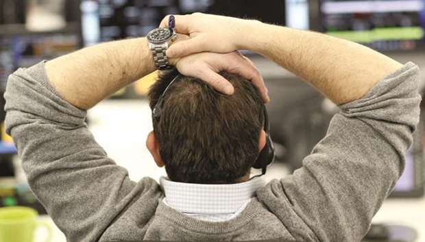 A broker looks at financial information on computer screens on the IG Index trading floor in London (file). The FTSE 100 fell 1.3% at 7,145.74 points at close yesterday.