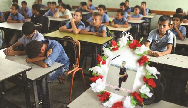 A picture of 12-year-old Palestinian boy Nassir al-Mosabeh, who was killed during a protest at the Israel-Gaza border fence, is seen on his table as his classmates react at a school, in Khan Younis in the southern Gaza Strip, yesterday.