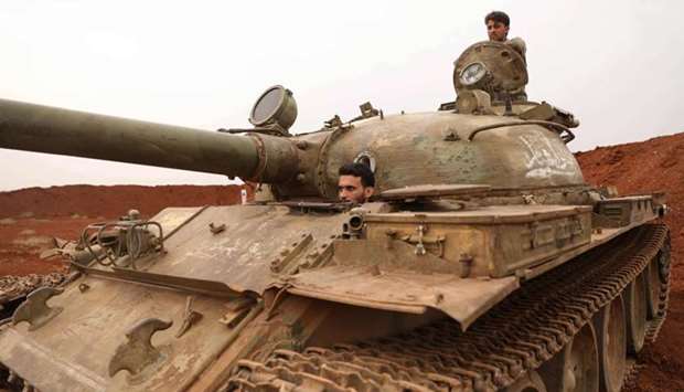 Syrian rebel-fighters from the National Liberation Front (NLF) secure a tank, part of heavy weapons and equipment withdrawn yesterday from a planned buffer zone around Idlib in one of the group's rear positions in a rebel-held area in the southwestern Syrian province on October 9.