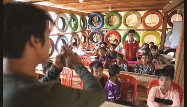 Ouk Vanday, known as the Rubbish Man, teaching students in a classroom with walls made from painted used car tyres at the Coconut School at Kirirom national park in Kampong Speu province.