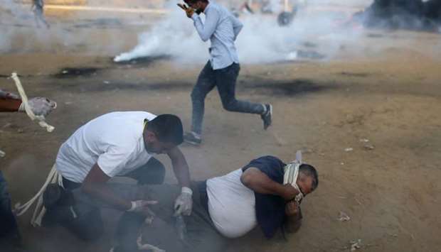 Palestinians react from tear gas fired by Israeli troops during a protest calling for lifting the Israeli blockade on Gaza and demanding the right to return to their homeland, at the Israel-Gaza border fence in the southern Gaza Strip.